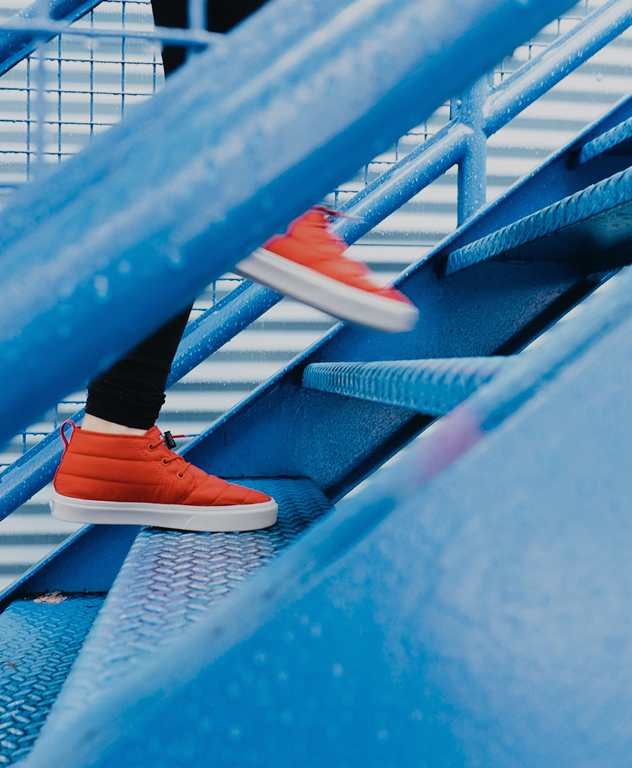 Orange shoes moving up bright blue stairs